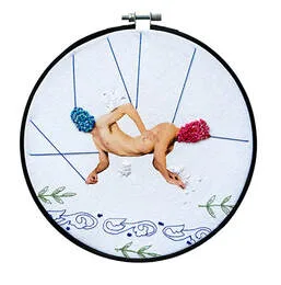 Embroidery and print displayed in a black embroidery hoop. Two male forms joined at the waist with face covered in brightly coloured french knots.